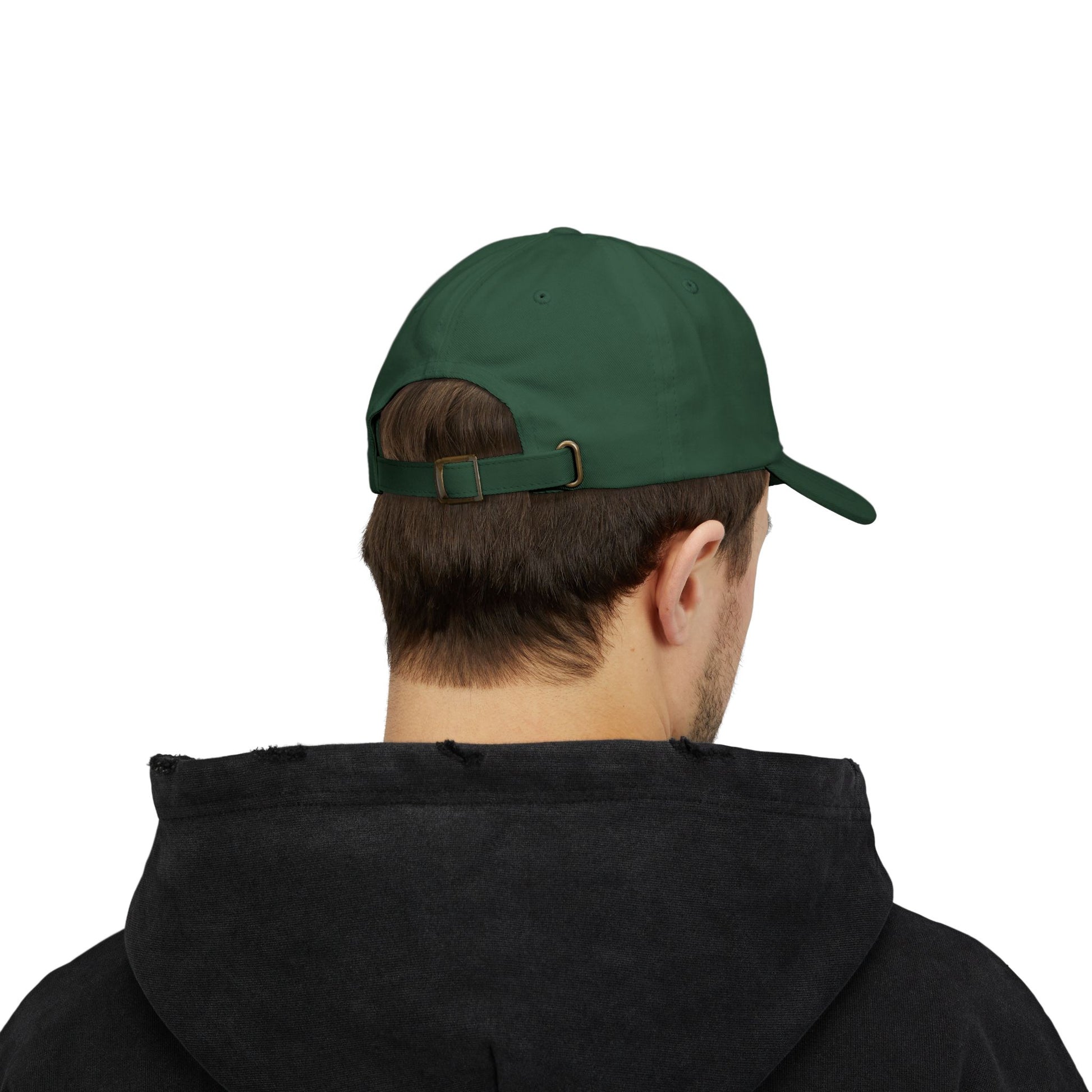 Back view of a person with short brown hair wearing a green cap from the Worldwide PRIDE store, featuring a rainbow design and the embroidered pronouns he/him. The person is also wearing a black hooded sweatshirt and looking down.