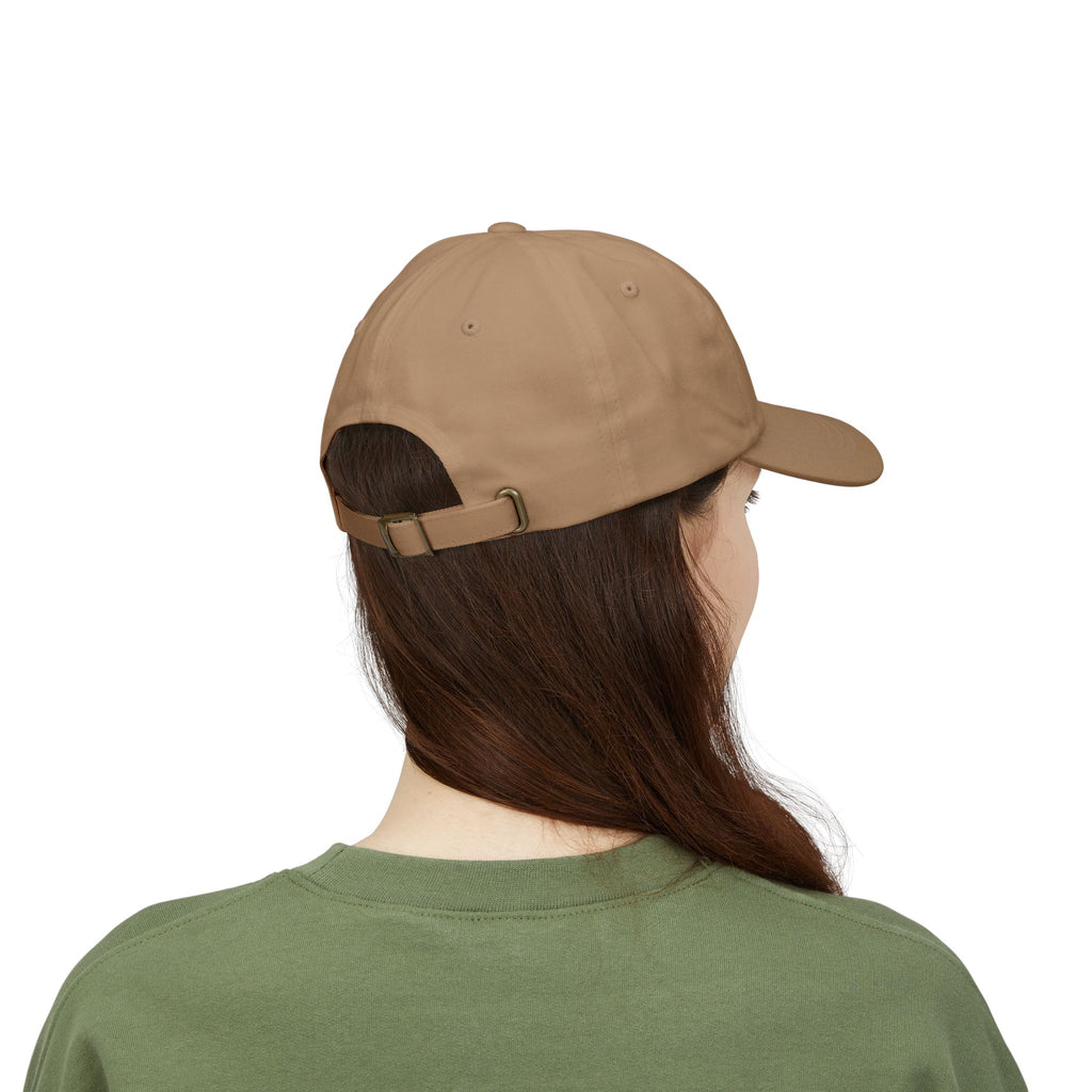 Back view of a person with long brown hair wearing a khaki cap from the Worldwide PRIDE store, featuring a rainbow design and the embroidered pronouns she/her, along with an olive green sweatshirt. 