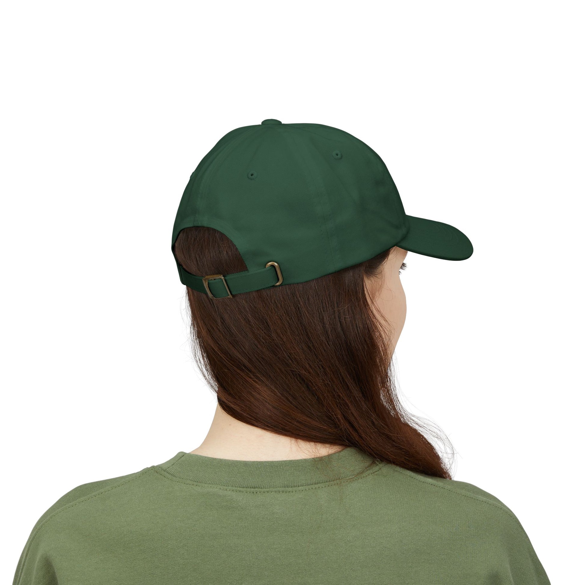 Back view of a person with long brown hair wearing a green cap from the Worldwide PRIDE store, featuring a rainbow design and the embroidered pronouns she/her, along with an olive green sweatshirt. 