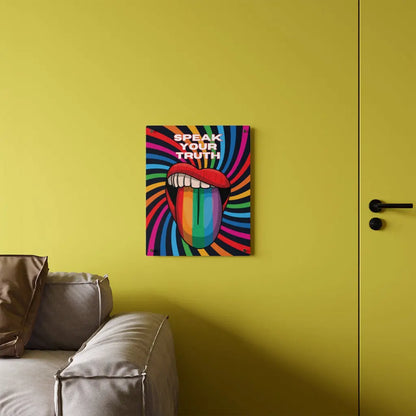 Worldwide PRIDE presents a vibrant piece of wall art that depicts an open mouth with rainbow-colored lips and tongue against a swirling rainbow backdrop. The words Speak Your Truth celebrate the LGBTQ community. The 16"x20" art sits on a yellow wall above a sofa.