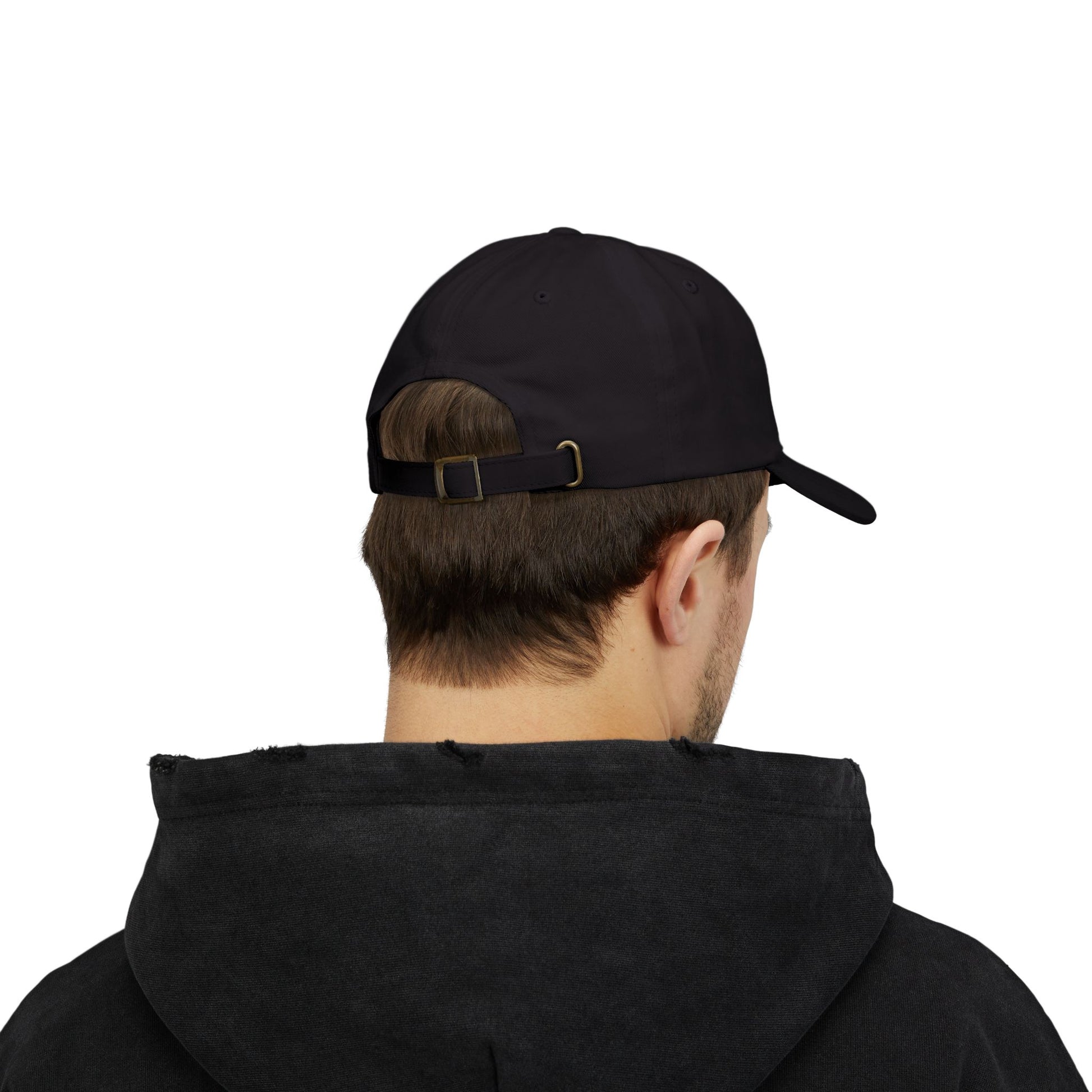 Back view of a person with short brown hair wearing a black cap from the Worldwide PRIDE store, featuring a rainbow design and the embroidered pronouns he/him. The person is also wearing a black hooded sweatshirt and looking down.