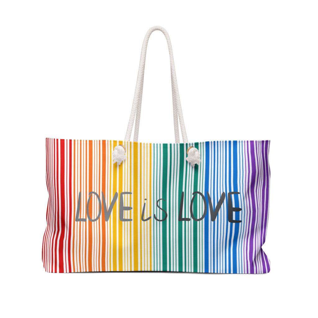 A weekender bag with rainbow stripes and the text Love is Love prominently in the center celebrates PRIDE. The bag, a tribute to the LGBTQ community, features white rope handles that stand out against a pristine white background.