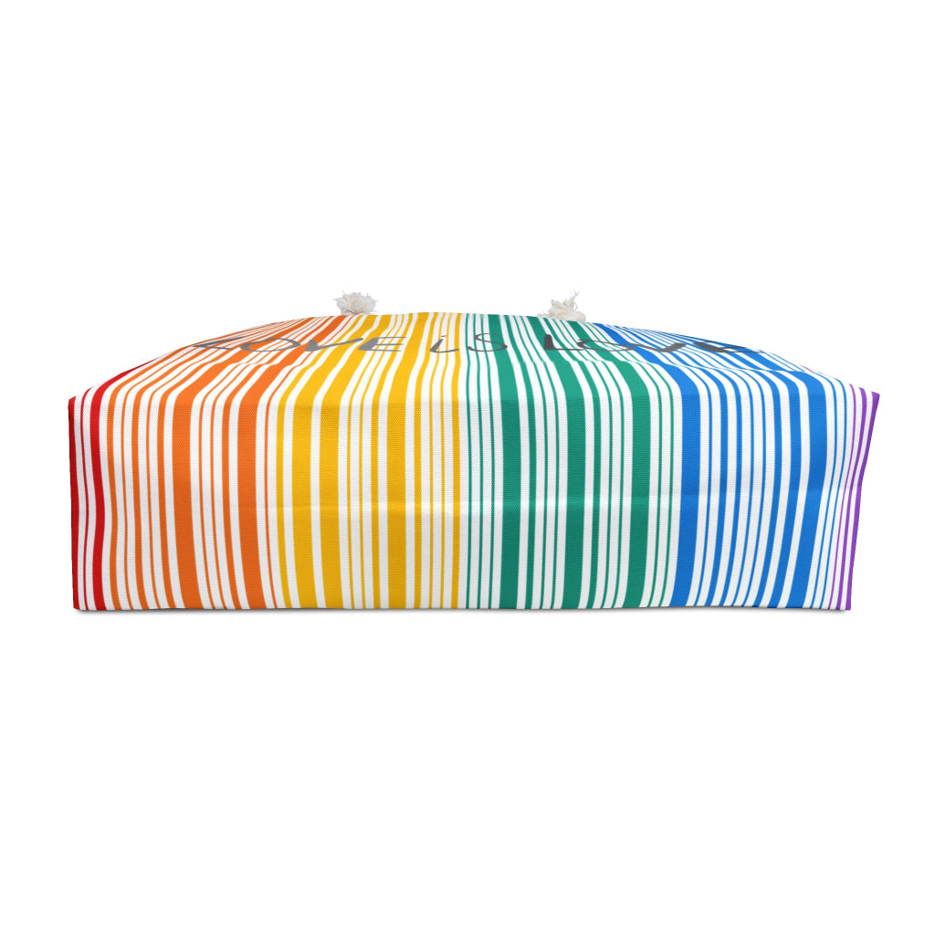 A photo of the bottom of a weekender bag with rainbow stripes that celebrates PRIDE. The bag, a tribute to the LGBTQ community, features white rope handles that stand out against a pristine white background.