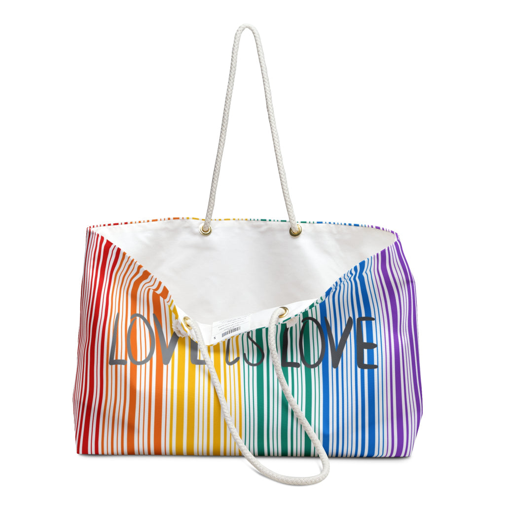 A weekender bag with rainbow stripes and the text Love is Love prominently in the center celebrates PRIDE. The bag, a tribute to the LGBTQ community, features white rope handles that stand out against a pristine white background.
