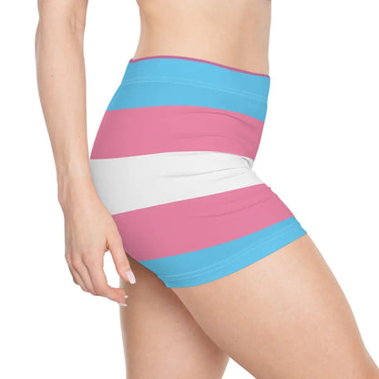 A person wearing colorful shorts with pink, blue, and white horizontal stripes echoes the design of the transsexual flag. Seen from the side, their hand casually rests on their hip, showcasing pride and style in one striking look.