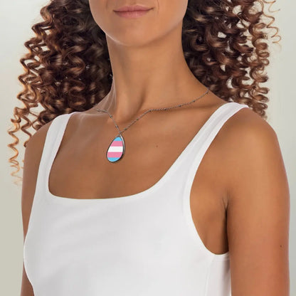 Person wears a teardrop-shaped necklace proudly displaying the colors and design of the transsexual flag. Carolina blue, pink and white colors symbolize the struggle and plight of the Trans community.