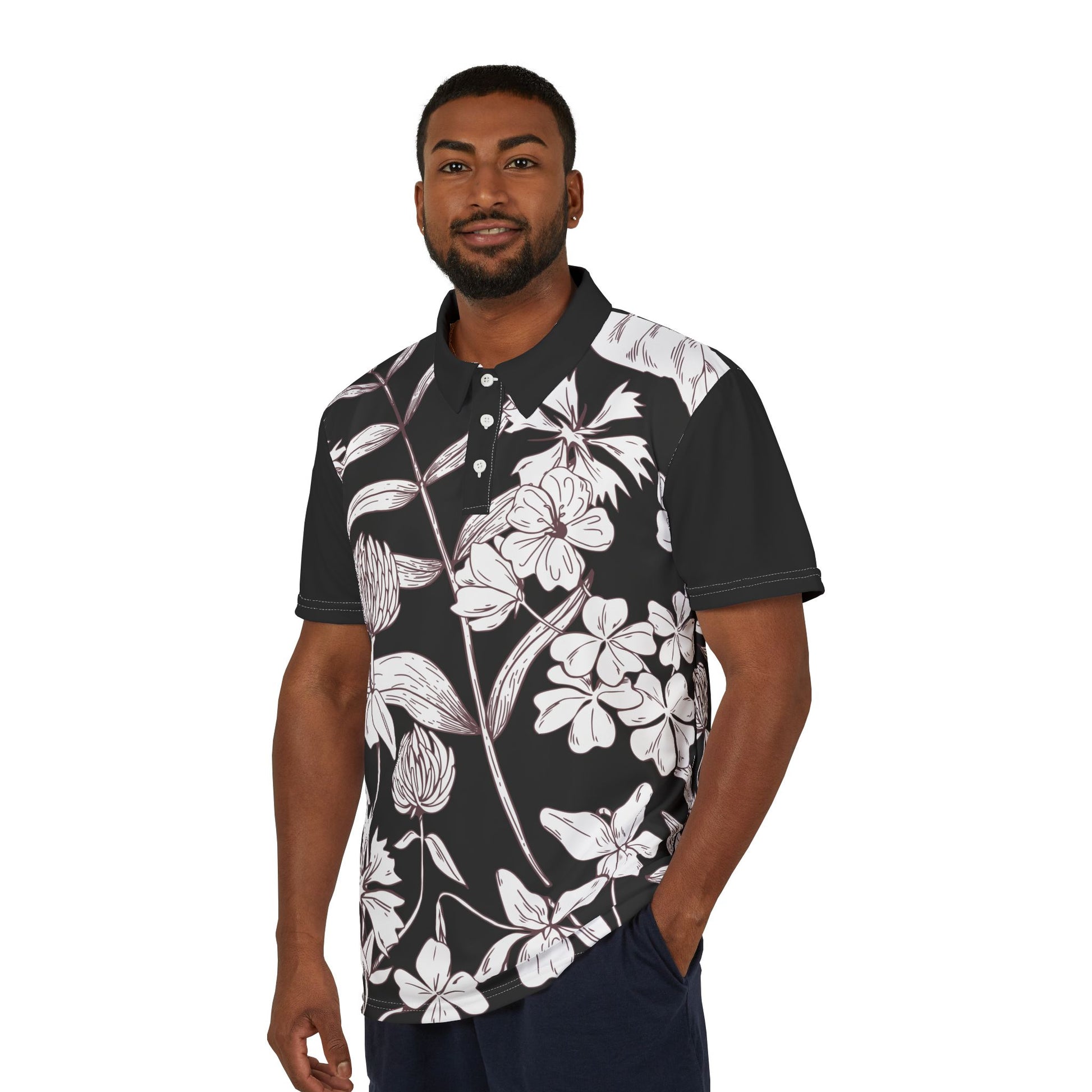 A person wears a black and white leaf and flower polo shirt from the Worldwide PRIDE Subtlety collection. On the right sleeve is a small colorful lion, an homage to the LBGTQ community. The person is placed against a plain white backdrop.