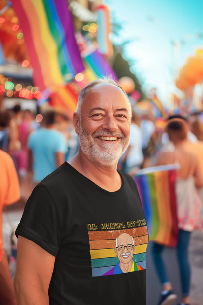 A person wearing a black unisex short-sleeve t-shirt with a graphic print of a person's face and the text 'ORIGINAL GAY-STER' in rainbow-colored letters.