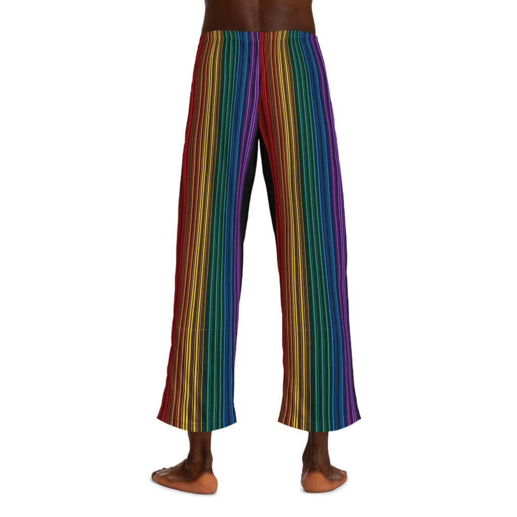 A person wearing colorful striped pants featuring vertical rainbow lines stands barefoot against a plain white background. Embracing the spirit of Worldwide PRIDE, these pants, with their drawstring waist, reflect the vibrant energy of the LGBTQ community. The persons upper body is not visible.