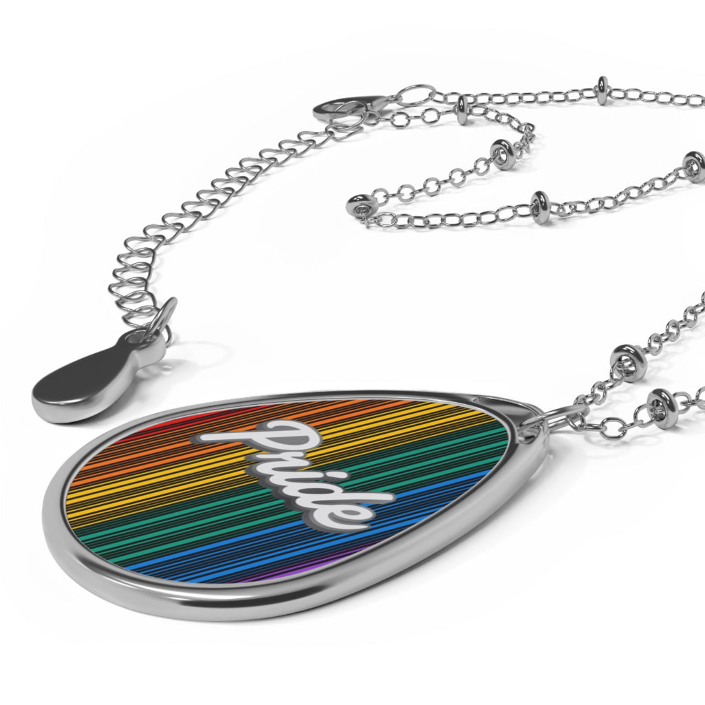 A silver chain necklace showcases a teardrop-shaped pendant adorned with a rainbow-striped pattern and the word PRIDE in elegant white cursive. The close-up captures the vibrant colors and shiny metal beautifully.