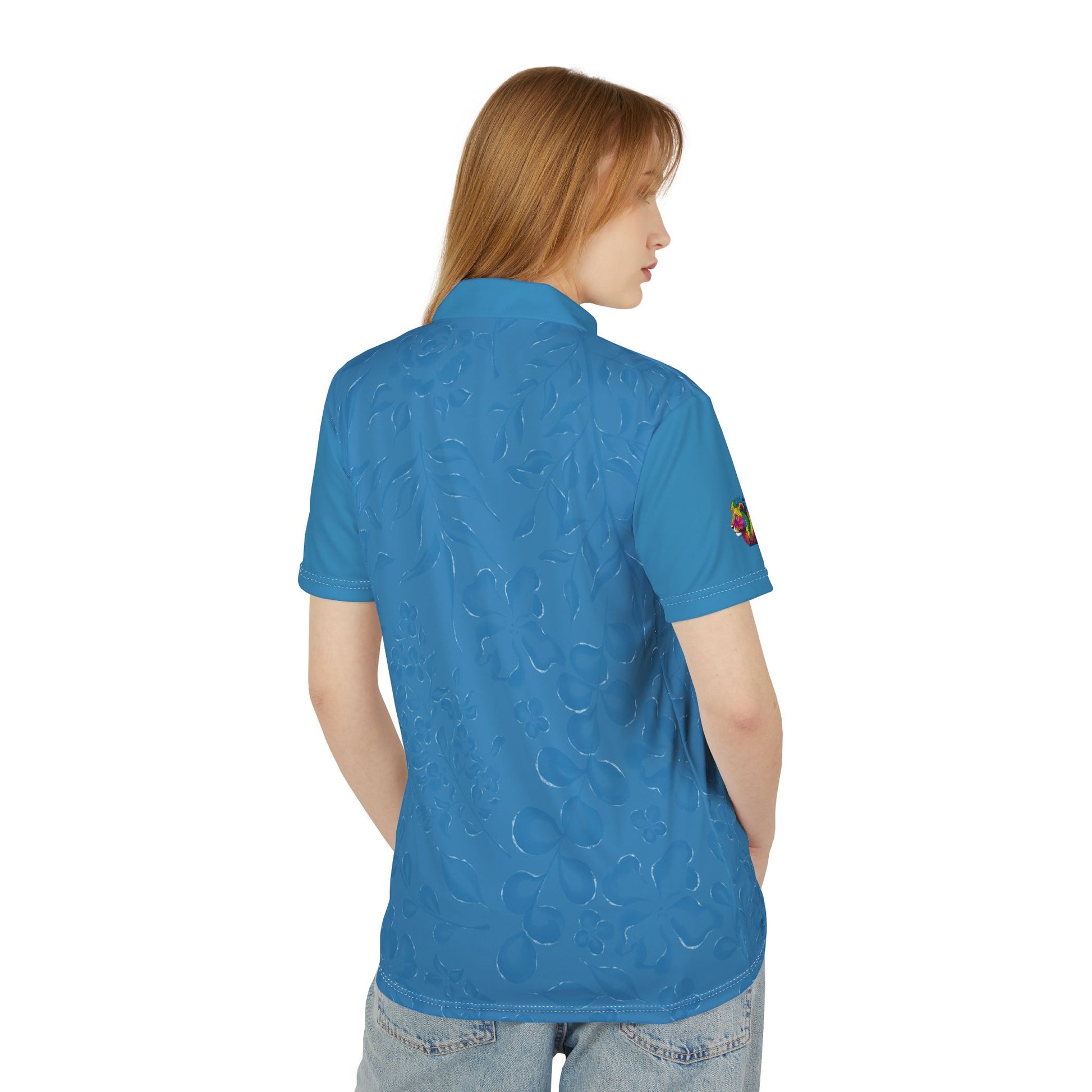 A person wears a blue polo shirt that features a flowery pattern with short sleeves and a vibrant lion on the right sleeve. It celebrates Worldwide PRIDE against a plain white backdrop.