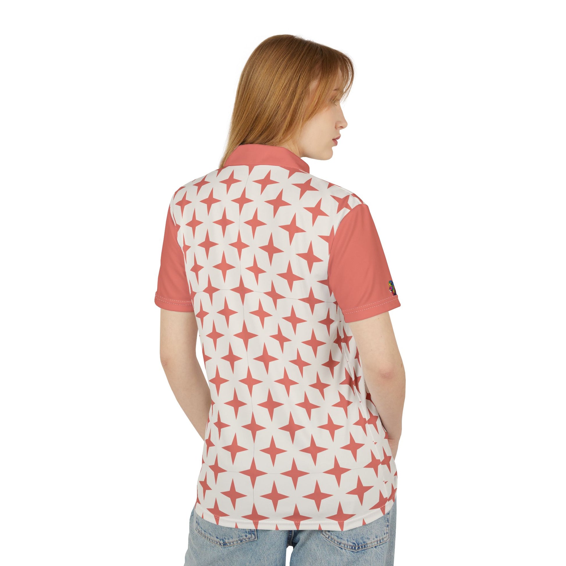 A person wears an eye-catching polo shirt featuring a coral collar and sleeves, with a white front and back adorned in coral stars. The shirt also features a small rainbow colored lion on the right sleeve. It's a subtle homage to the LGBTQ community.