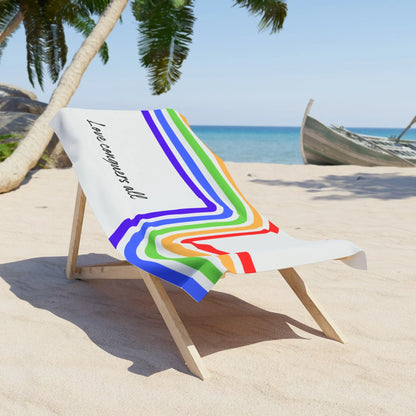 Beach towel with rainbow design and text on a wooden chair at the beach