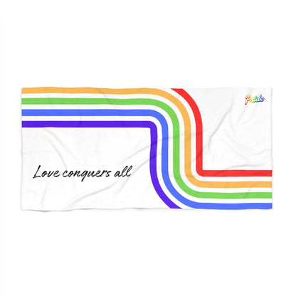 Towel with rainbow stripes and 'Love conquers all' text on a white background