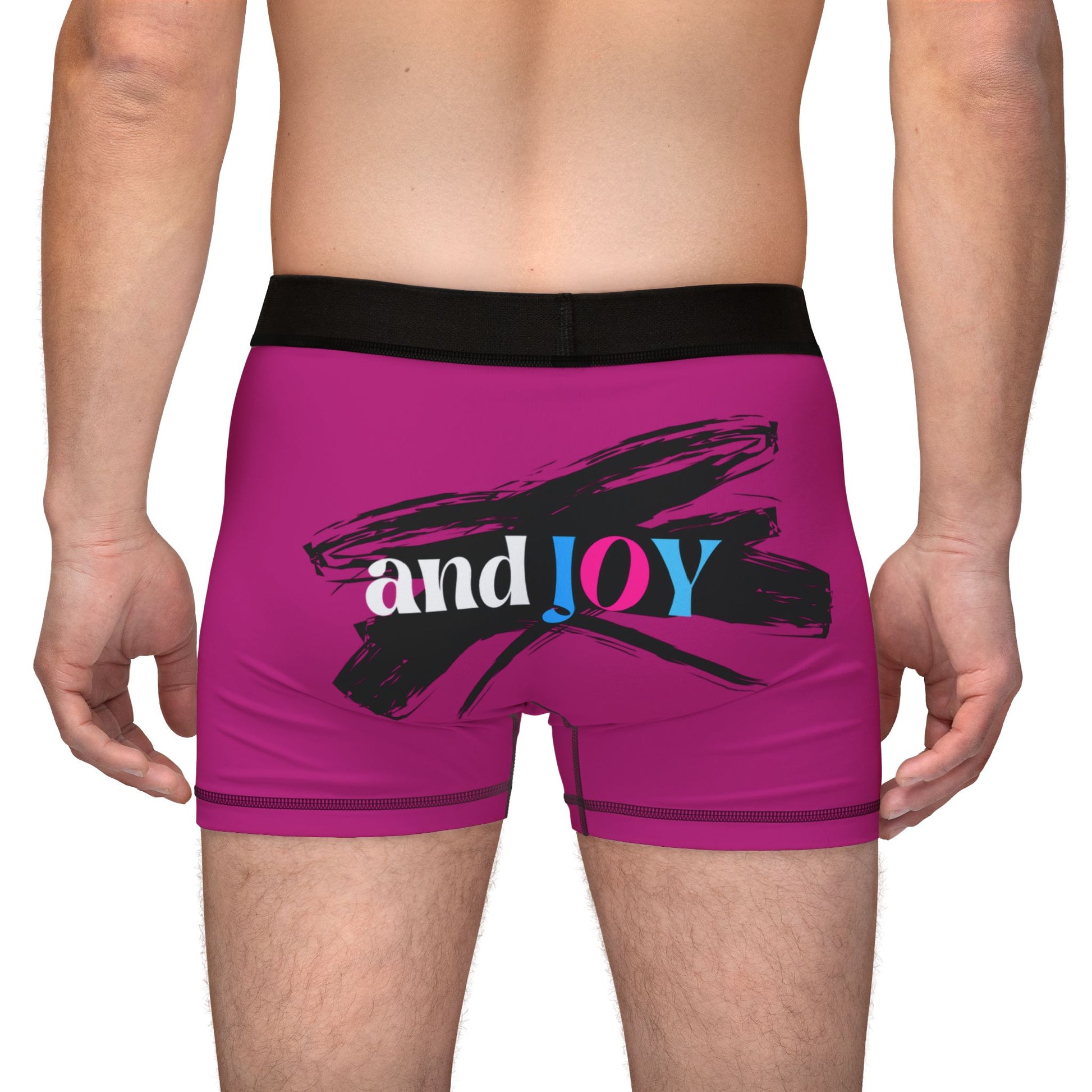 A person wearing pink boxer briefs with a black waistband, proudly showcasing My PRIDE in colorful letters on the front and and JOY on the back. This vibrant design celebrates the worldwide PRIDE and spirit of the LGBTQ community.