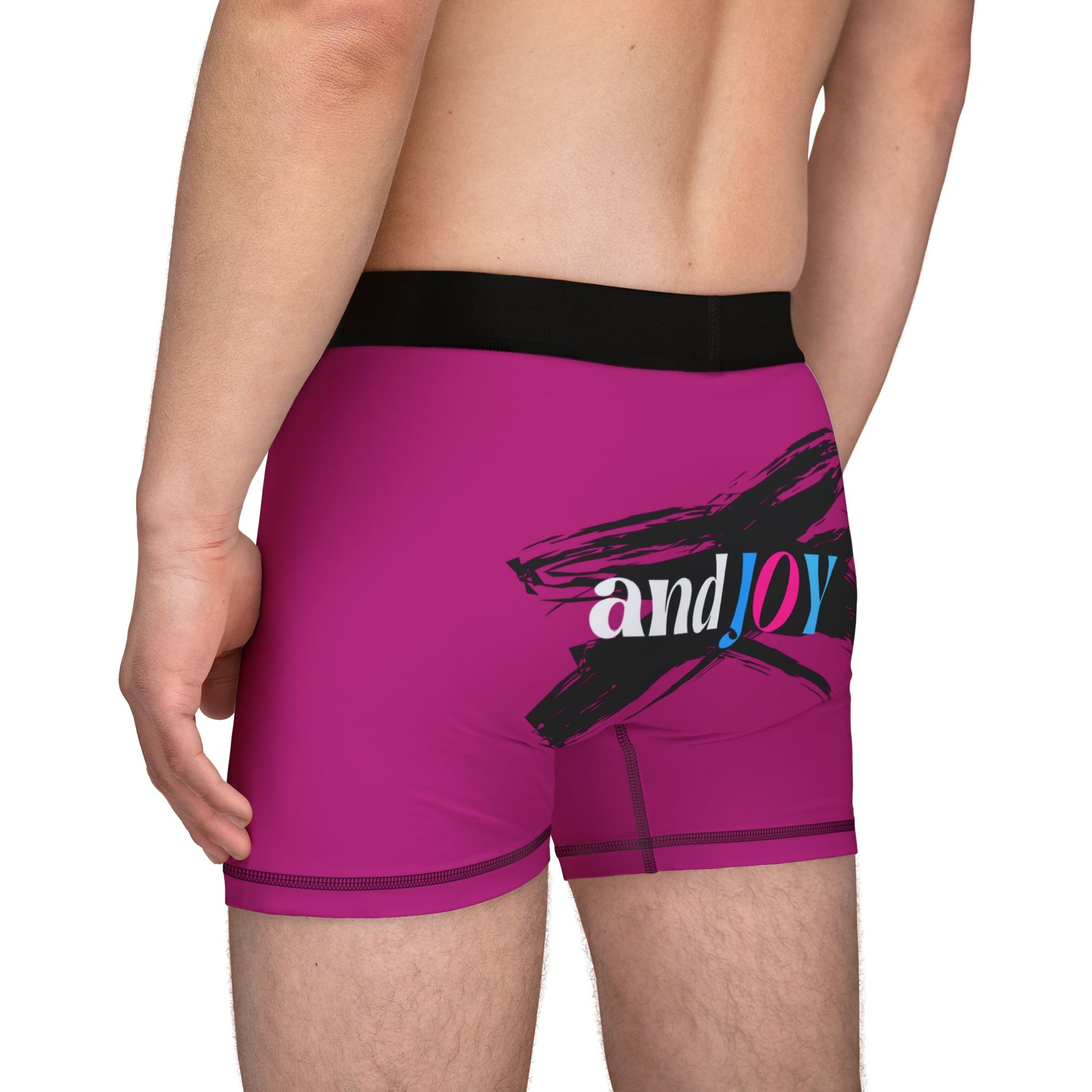 A person wearing pink boxer briefs with a black waistband, proudly showcasing My PRIDE in colorful letters on the front and and JOY on the back. This vibrant design celebrates the worldwide PRIDE and spirit of the LGBTQ community.