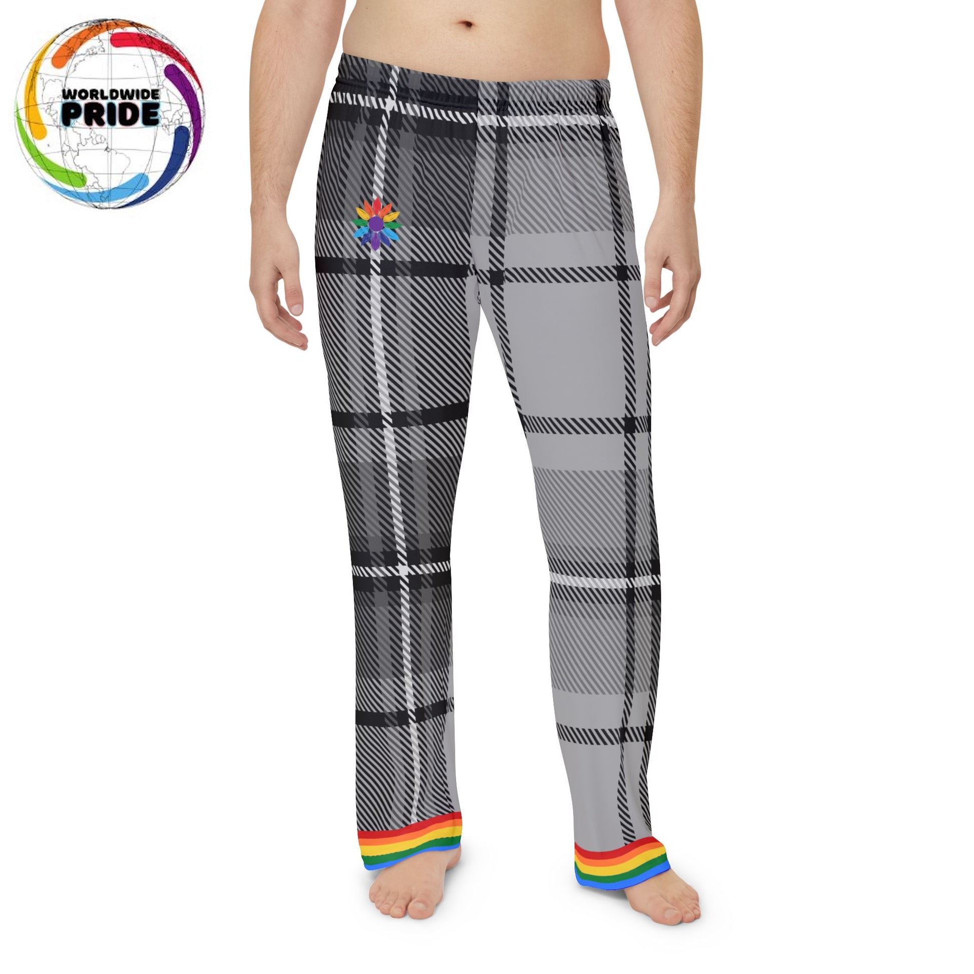 A person is standing barefoot, wearing gray and black plaid pants with a rainbow trim at the cuffs. The persons torso is not covered by any clothing. The pants feature a subtle rainbow-pedaled flower near the waistband. The background is plain white.