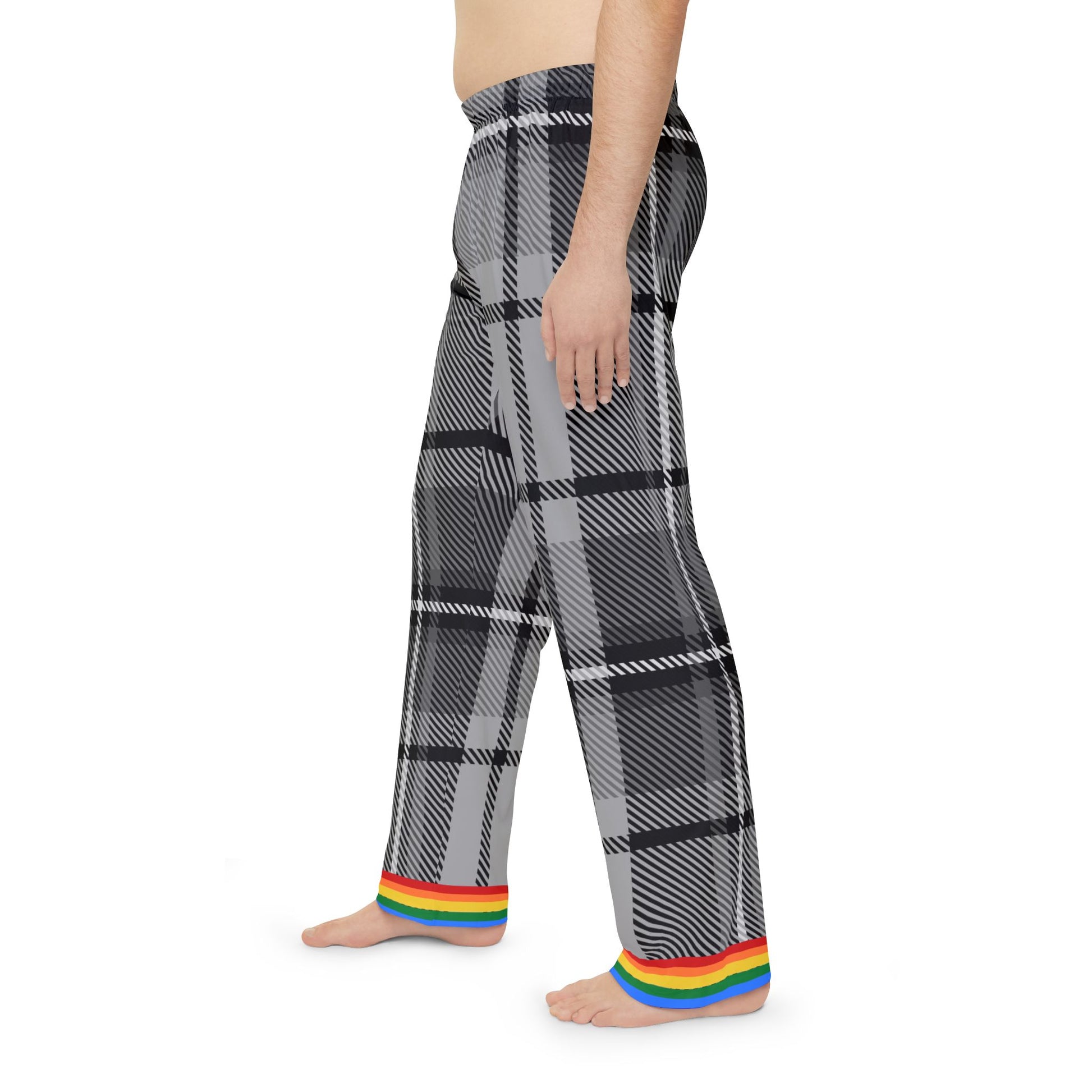 A person is standing barefoot, wearing gray and black plaid pants with a rainbow trim at the cuffs. The persons torso is not covered by any clothing. The pants feature a subtle rainbow detail near the waistband. The background is plain white.