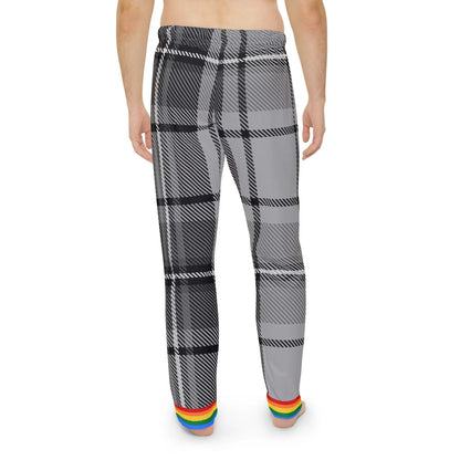 A person is standing barefoot facing away from the camera. They are wearing gray and black plaid pants with a rainbow trim at the cuffs. The persons torso is not covered by any clothing. The background is plain white.