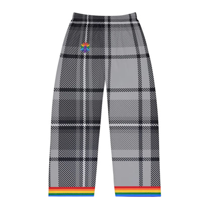 A photo of gray and black plaid pants with a rainbow trim at the cuffs. The pants feature a subtle rainbow-pedaled flower detail near the waistband. The background is plain white.