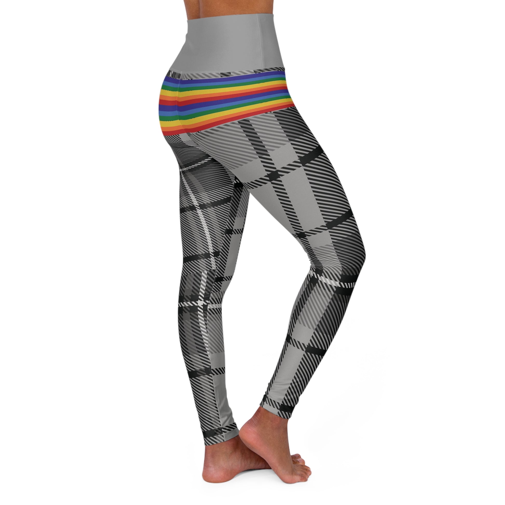 Person wearing leggings with a grey waistband, rainbow-striped midsection, and black-and-white plaid pattern on the legs. The person is barefoot and standing against a white background.