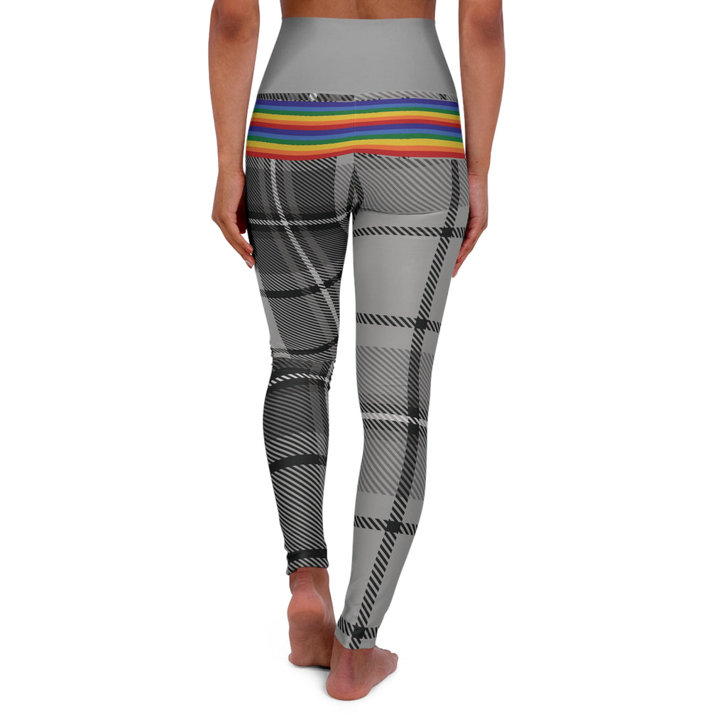 Person wearing leggings with a grey waistband, rainbow-striped midsection, and black-and-white plaid pattern on the legs. The person is barefoot and standing against a white background.