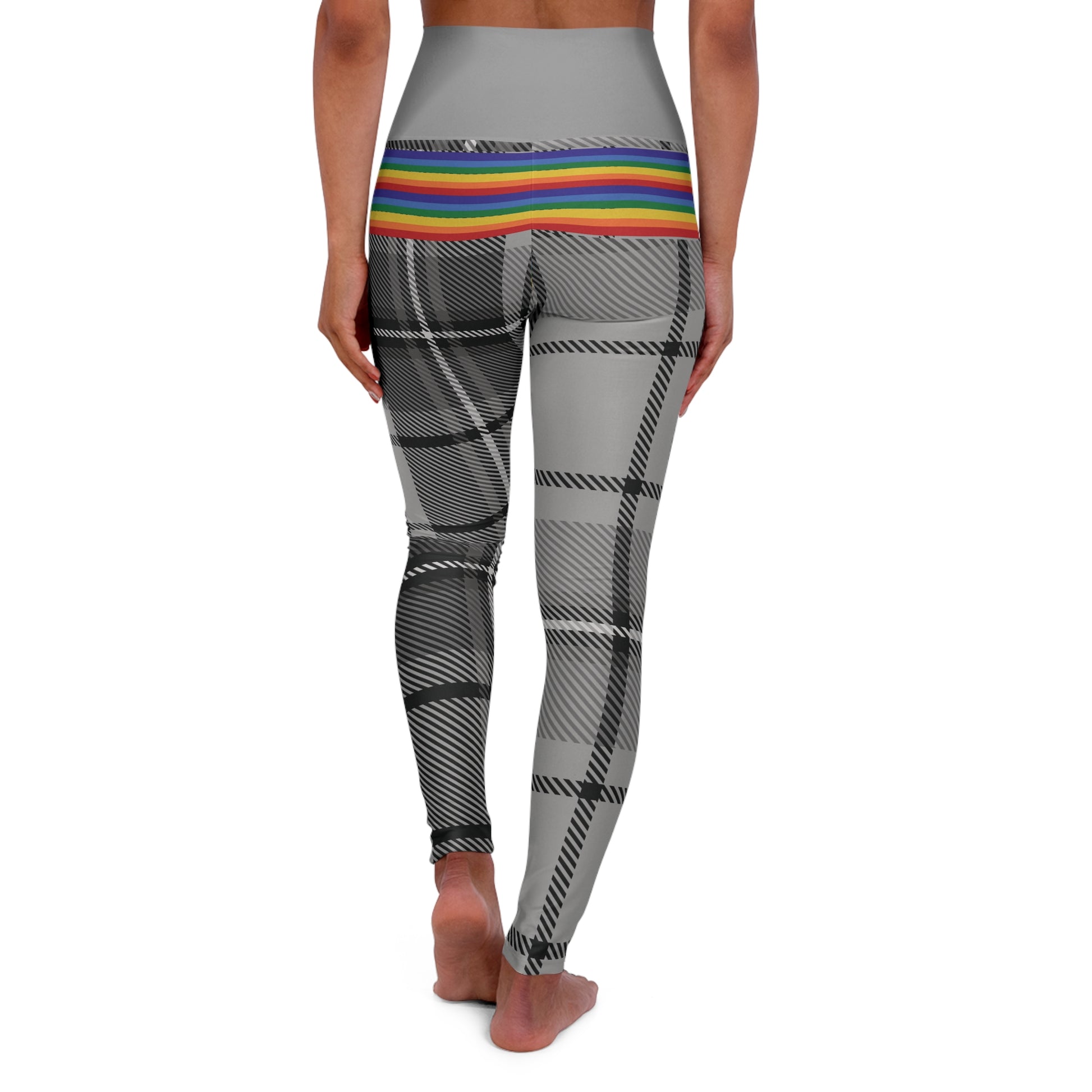 Person wearing leggings with a grey waistband, rainbow-striped midsection, and black-and-white plaid pattern on the legs. The person is barefoot and standing against a white background.