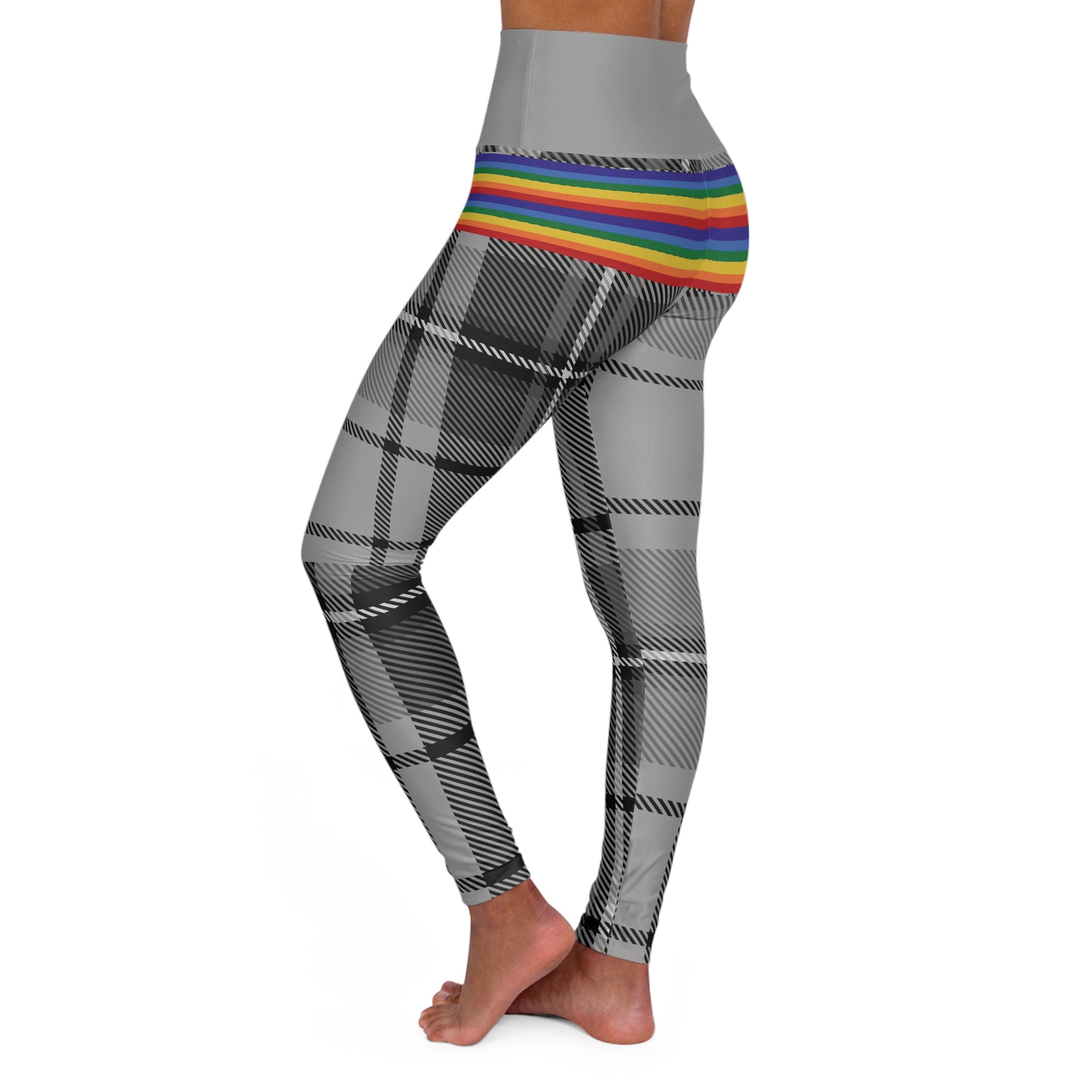 Person wearing leggings with a grey waistband, rainbow-striped midsection, and black-and-white plaid pattern on the legs. The person is barefoot and standing against a white background.