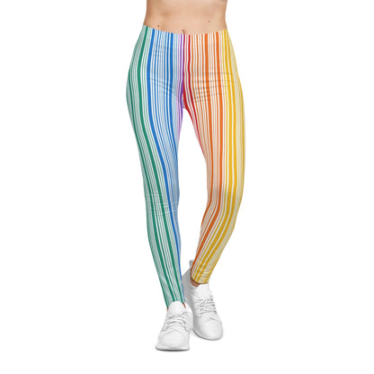 A person wearing colorful leggings with vertical stripes in a gradient from blue to red embodies the spirit of PRIDE. They are also wearing white sneakers and standing against a plain white background, celebrating vibrancy and diversity.