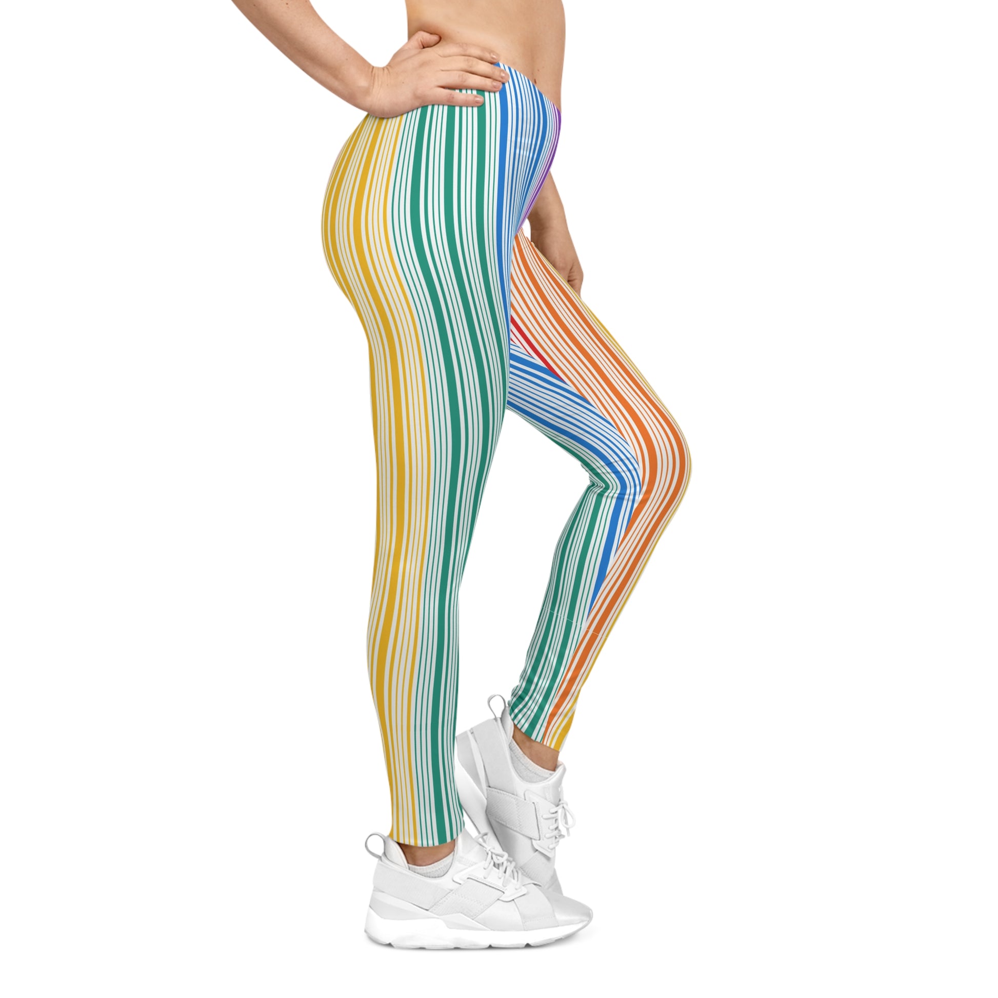 A person wearing colorful leggings with vertical stripes in a gradient from blue to red embodies the spirit of PRIDE. They are also wearing white sneakers and standing against a plain white background, celebrating vibrancy and diversity.