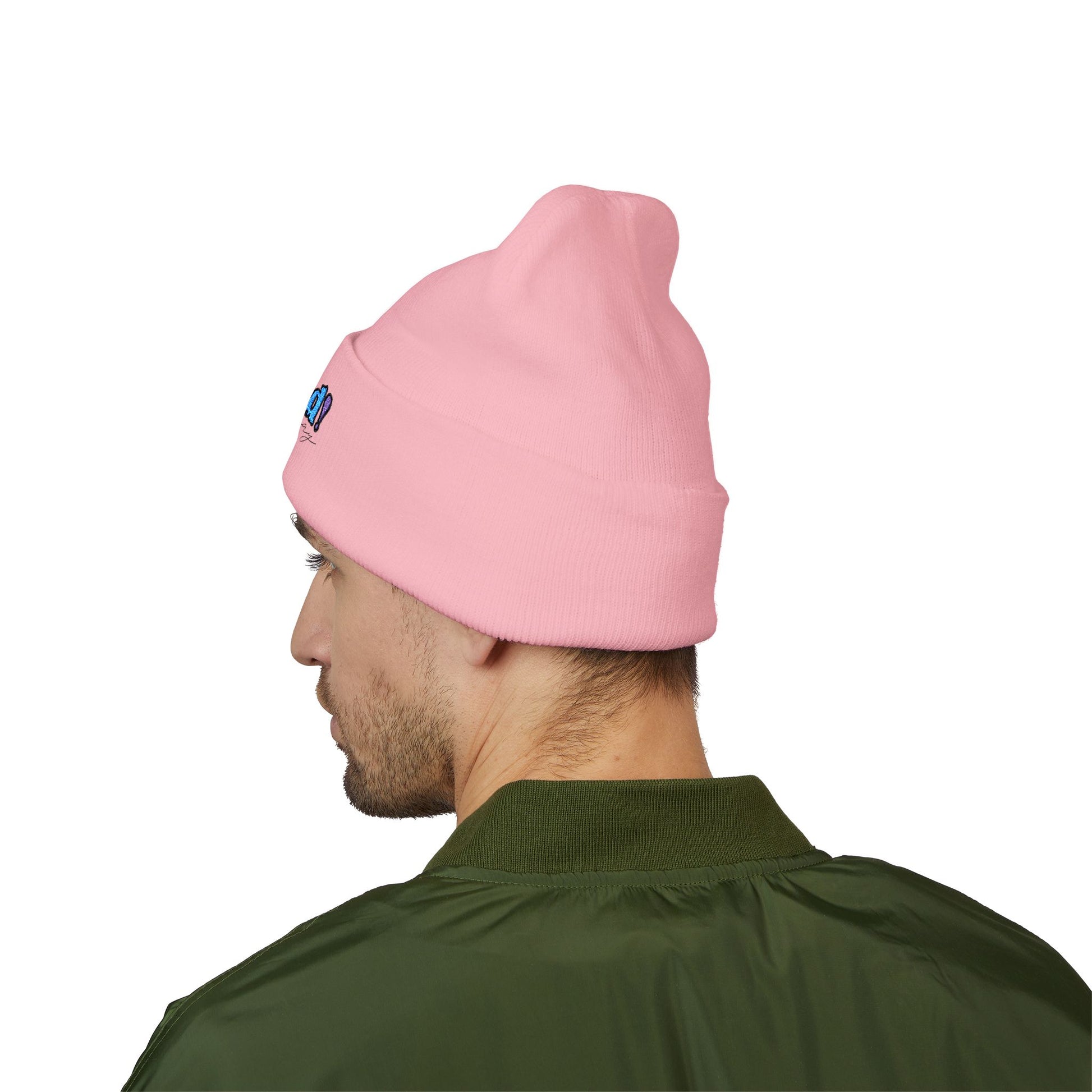 Back view of a person wearing a light pink beanie with “proud everyday" embroidered in rainbow colors and a green jacket, looking slightly to the side with a neutral expression. Perfect for the LGBTQ community from the Worldwide PRIDE store.