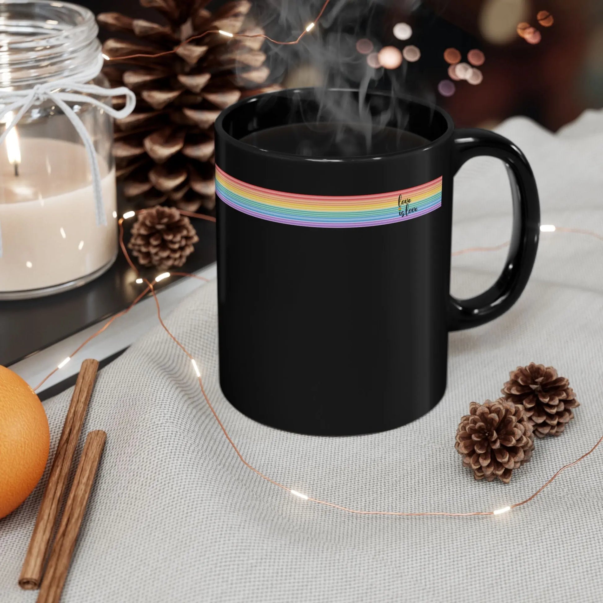Black mug with rainbow band and logo on a table with decorative items