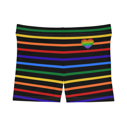 A pair of women's shorts featuring a striped pattern a glittery heart, and vibrant rainbow colors on a black background.
