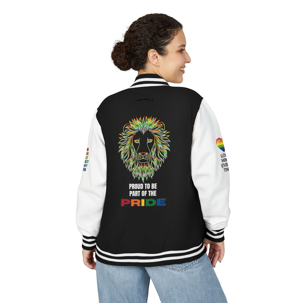 A person stands smiling showing the back of a black and white letterman jacket featuring a rainbow-colored lion face, the text PROUD TO BE PART OF THE PRIDE, and rainbow heart designs with positive messages on both sleeves.