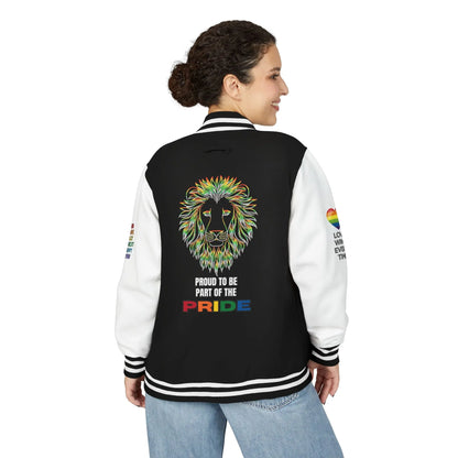 A person stands smiling showing the back of a black and white letterman jacket featuring a rainbow-colored lion face, the text PROUD TO BE PART OF THE PRIDE, and rainbow heart designs with positive messages on both sleeves.