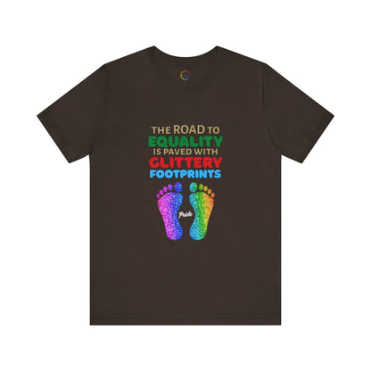 A brown unisex short-sleeve t-shirt with a graphic of multicolored glitter footprints and the text 'THE ROAD TO EQUALITY IS LITTERED WITH GLITTERY FOOTPRINTS'.