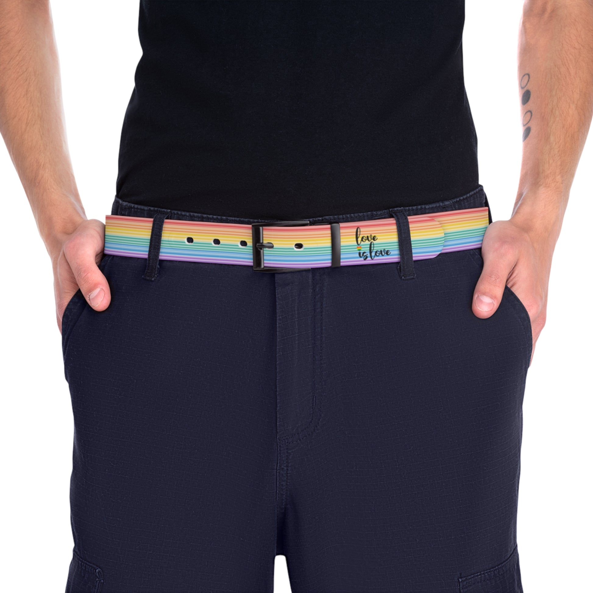 A person wearing a black shirt and black slacks with the Worldwide-PRIDE rainbow-striped Love is Love belt with black buckle, showing support for the LGBTQ+ community, with one hand in their pocket.