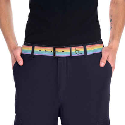 A person wearing a black shirt and black slacks with the Worldwide-PRIDE rainbow-striped Love is Love belt with black buckle, showing support for the LGBTQ+ community, with one hand in their pocket.