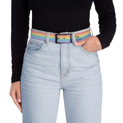A person wearing a black long-sleeve shirt and light blue jeans with the Worldwide PRIDE rainbow-striped Love is Love belt with black buckle, showing support for the LGBTQ+ community, with one hand in their pocket.