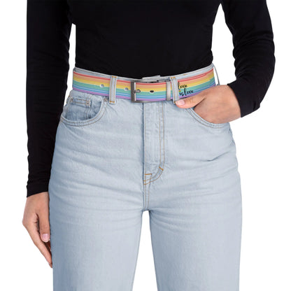 A person wearing a black long-sleeve shirt and light blue jeans with the Worldwide PRIDE rainbow-striped Love is Love belt with gun metal buckle, showing support for the LGBTQ+ community, with one hand in their pocket.