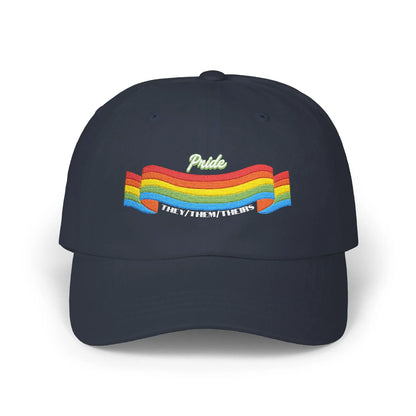 A navy blue cap from the Worldwide PRIDE store, featuring a rainbow design and the embroidered pronouns they/them/theirs.