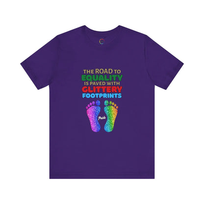 A purple unisex short-sleeve t-shirt with a graphic of multicolored glitter footprints and the text 'THE ROAD TO EQUALITY IS LITTERED WITH GLITTERY FOOTPRINTS'.