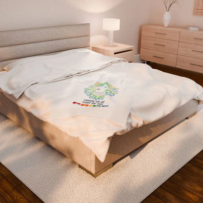 White throw blanket with rainbow lion design and 'Proud to be part of the Pride' text on a bed.