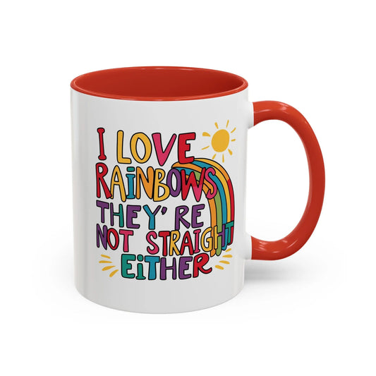 A white ceramic coffee mug with a red handle and interior, featuring the colorful text 'I LOVE RAINBOWS THEY'RE NOT STRAIGHT EITHER' along with a graphic of a rainbow and a sun.