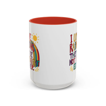 A white ceramic coffee mug with a red handle and interior, featuring the colorful text 'I LOVE RAINBOWS THEY'RE NOT STRAIGHT EITHER' along with a graphic of a rainbow and a sun.