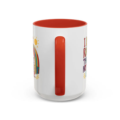 A white ceramic coffee mug with a red handle and interior, featuring the colorful text 'I LOVE RAINBOWS THEY'RE NOT STRAIGHT EITHER' along with a graphic of a rainbow and a sun.